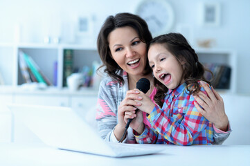  mother and daughter using laptop together singing