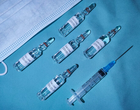 Coronavirus vaccine syringe mask on blue background. COVID-19 vaccine