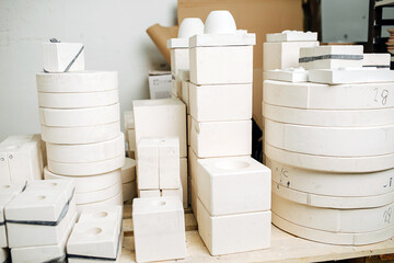 Stack of molds for casting tableware of different size and shape. In a storage room in a workshop.