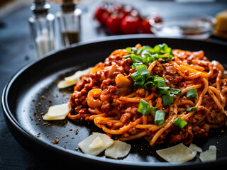 Spaghetti bolognese with minced pork meat and parmesan on black table