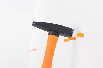 hammer hammering corks into white concrete wall, close-up