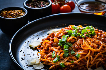 Spaghetti bolognese with minced pork meat and parmesan on black table