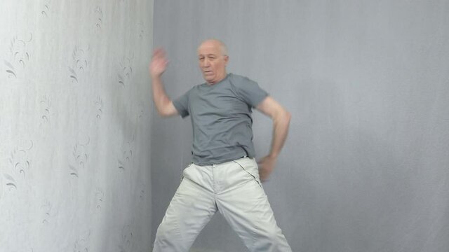 Old man in sportswear performs exercises with his hands