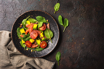 Healthy salad with fresh baby spinach, cherry tomatoes, avocado and salmon fish