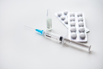 Preparation for vaccination against covid-19. Syringe, vaccine, pills, medical mask on a white...
