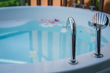 Bathtub outside at the balcony with tropical flowers in luxury hotel.