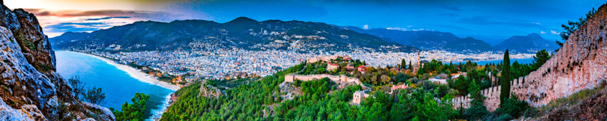 Aerial panorama of Alanya, Turkey with castle, mountains, city and coastline, blue hour at night