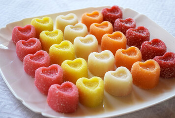 Marmalade heart-shaped candies. Colorful bright marmalade sweets on white plate on a White Background. Heart candies coated with sugar. Candy Valentines Hearts.