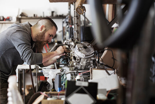Serious mechanic working on motorcycle engine at auto repair shop