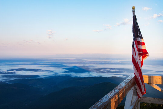 American flag on railing of fire lookout tower against landscape