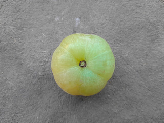 a beautiful green coloured amala's fruit on brown background, it's uses in production of medicine