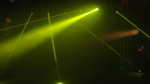 Colorful stage lights lighting up dark studio. Strobe white spotlights and yellow laser holograms emits light bright beams. Lighting equipment, light effects for during show, disco or party. Close up.