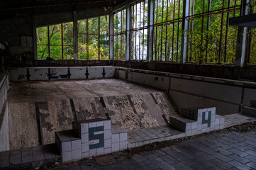 empty rotten swimming pool in abandoned school defeated by forest going inside the building 
