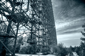 huge abandoned rusty antenna from Soviet Union time in black and white with clouds and sky