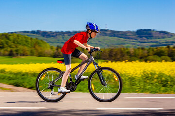 Fototapeta premium Teenage boy cycling on country road 