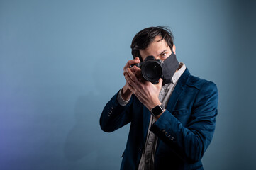 Portrait of positive photographer, man with medical mask holding professional digital dslr camera