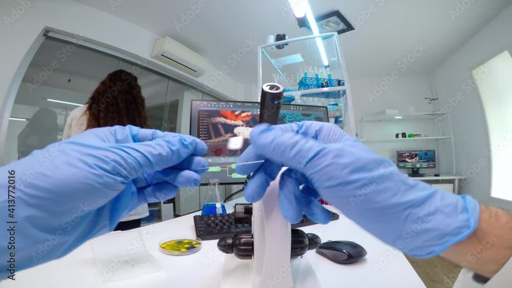 Poster pov of scientists working in lab with patri dish looking into microscope blood analysis. medical stu