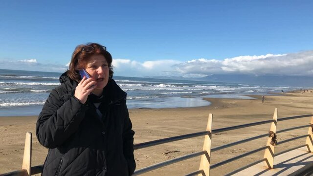  woman talking on smartphone in front of the sea