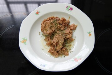 Spicy tuna fish canned meat with oregano and olive oil on a plate. Top view, selective focus