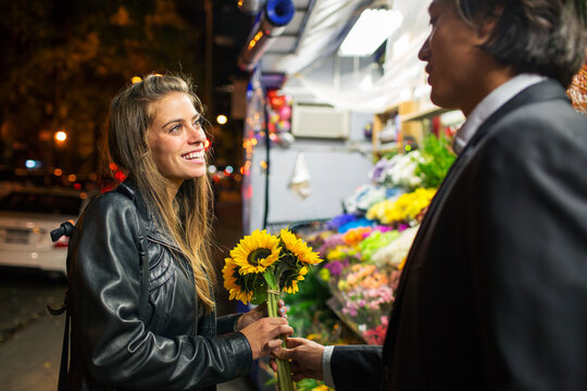 Man giving sunflowers to girlfriend while standing by flower shop