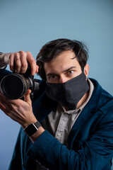 Portrait of positive photographer, man with medical mask holding professional digital dslr camera