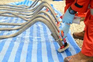 Worker are apply the penetrate to the welding of stainless steel pipe with a brush for finding the...