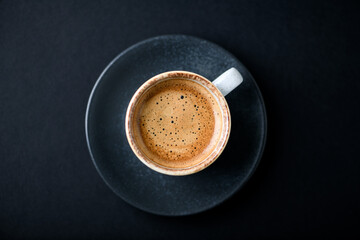 Cup of coffee on black background. Top view. Copy space	