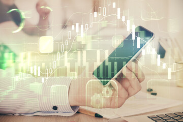 Fototapeta premium Double exposure of man's hands holding and using a digital device and forex graph drawing. Financial market concept.
