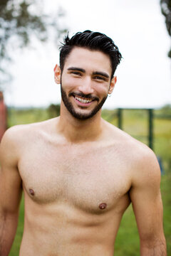 Portrait of happy shirtless man standing at yard