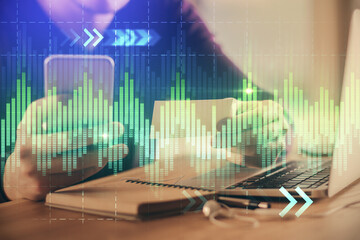 Double exposure of man's hands holding and using a phone and financial graph drawing. Analysis concept.
