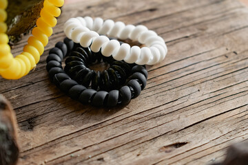 Naklejka premium Fashionable and modern elastic hair springs. Different colors of stretching hand bracelets on wooden background, stand