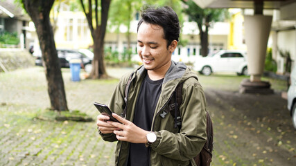 Asian people wear backpacks while holding cellphone