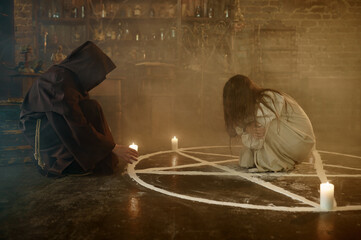 Exorcist in hood casting out devil from a woman