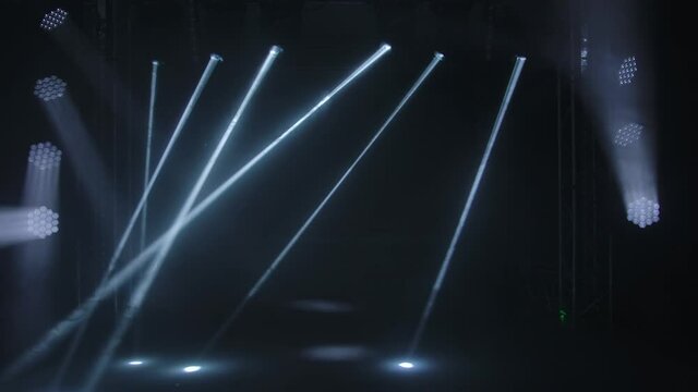 Colorful stage lights. White spotlights and laser holograms spins, turns and emits light bright beams. Lighting equipment and light effects for concert hall and stage lighting during show or disco.