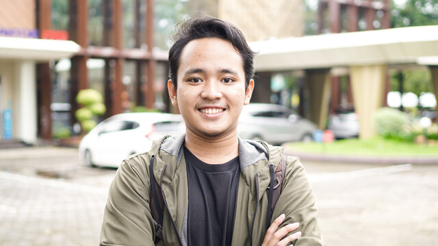 Portrait of smiling Asian man with backpack standing and staring at the camera