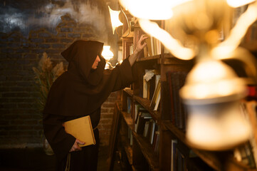 Exorcist in black hood choosing book of spells