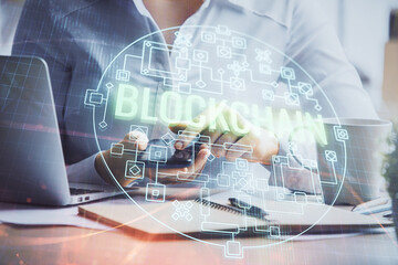 Double exposure of blockchain business sketch hologram and woman holding and using a mobile device.