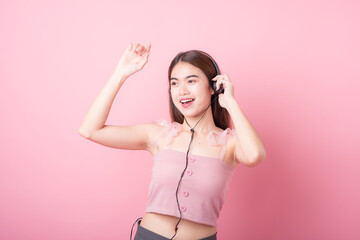 Happy smiling young asia woman with headphones enjoying listens to music over pink background