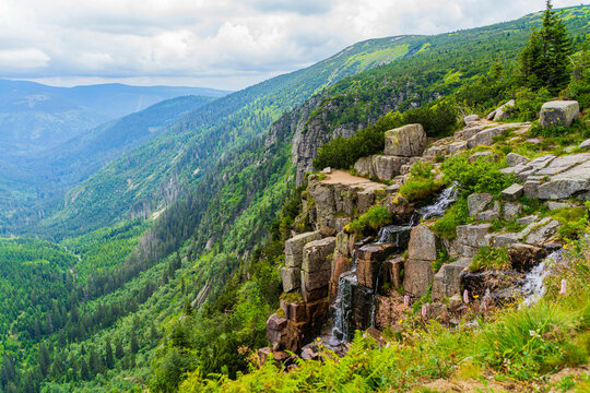 high waterfall with a beautiful landscape of the mountains in the Czech Republic