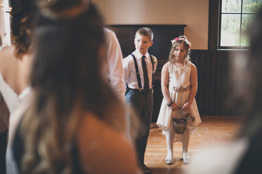Flower girl with pageboy looking at bride during wedding ceremony