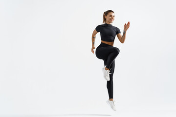 Healthy sport woman with fit body raising leg, jumping and exercising on white background. Female...