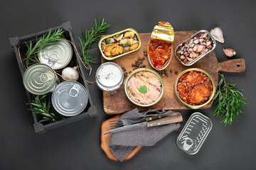 Various canned fish and seafood in aluminum cans. On dark gray background.