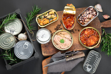 Various canned fish and seafood in aluminum cans. On dark gray background.