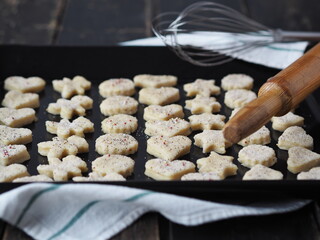 Raw shortbread cookies, sprinkled with sugar, on a baking sheet from the kitchen oven with kitchen utensils on a dark wooden table.Confectionery background.