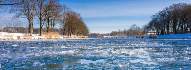 Wasserkanal eingefroren im Winter bei eisigen minus Temperaturen in Deutschland. Luftaufnahmen beim sonnigen Tag im Februar.