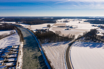 Wasserkanal in einer Stadt eingefroren im Winter bei eisigen minus Temperaturen in Deutschland. Luftaufnahmen beim sonnigen Tag im Februar über eingefrorene Straßen und Ackerbau.