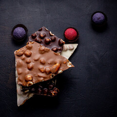 Chocolate candy truffle with chocolate pieces and flying cocoa powder on a dark background