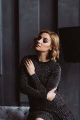 Portrait of a beautiful blonde woman in a black dress with smoky eye makeup in a loft interior. Soft selective focus.