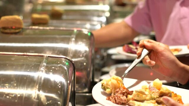 People hand grab some buffet food on their own plate in hotel seminar