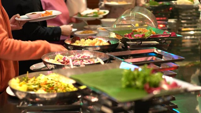 People hand grab buffet food in hotel restaurant